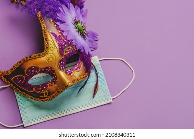 Concept of carnival during covid-19. Venetian carnival mask with protective surgical mask over purple background. Carnival celebration concept - Shutterstock ID 2108340311