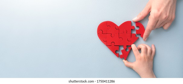 The Concept Of Charity, Love, Donate And Helping Hand. International Cardiology Day. A Woman And Child Arranges Red Heart Shape Puzzles. Symbol Of Helping Others.