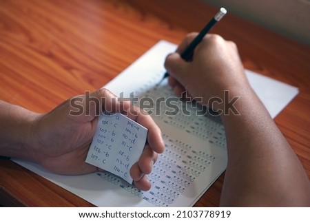 Concept : Cheat the test. Selective focus on hand hold small piece of paper that wrote answer during doing test.                                   