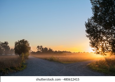 Concept Of Choice The Correct Way. Beautiful Landscape With Sunrise Over Crossroads Spliting In Two Ways. Rural Crossroads On Sunset Background