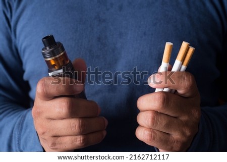 Concept of choosing the type of cigarette, a man's hand holds both types of cigarettes to choose from.