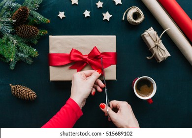 Concept of Christmas items on a table. Woman's hands wrapping Christmas gift