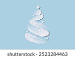 The concept of a Christmas tree in the form of cosmetic touches on a blue background. Moisturizing the skin in winter. Winter concept.