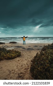 Concept Of Climate Change For Global Warming People. Man Standing Against Bad Weather With Black And Blue Clouds And Flood Water Ground. Adventure People At The Beach And Epic Landscape