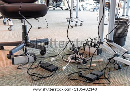 Concept of clutter in office. Unwound and tangled electrical wires under the table. 5S system of lean manufacturing
