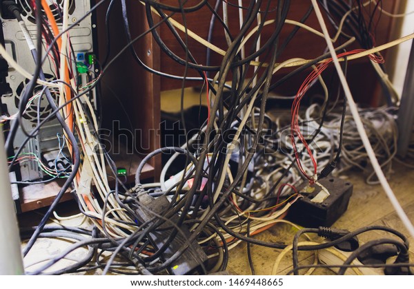 Concept of clutter in office. Unwound and\
tangled electrical wires under the\
table.