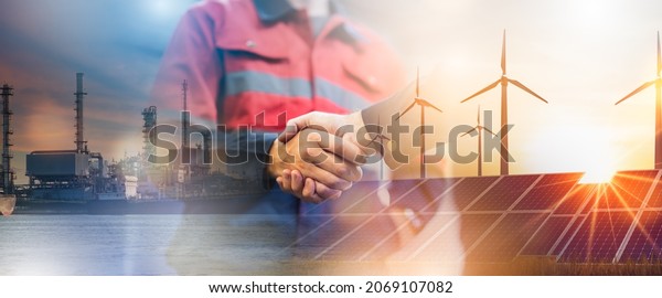 Concept of collaboration to change the world to\
reduce global warming,energy sources for renewable,sustainability\
by alternative energy.Double exposure of handshake of wind turbine\
and night city.