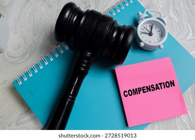Concept of compensation write on sticky notes isolated on Wooden Table. Representing legal damage, court decision and financial settlement