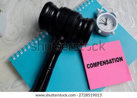 Concept of compensation write on sticky notes isolated on Wooden Table. Representing legal damage, court decision and financial settlement
