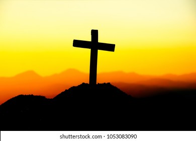Concept conceptual cross religion symbol silhouette in nature over sunset or sunrise sky