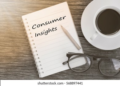 Concept Consumer Insights Message On Notebook With Glasses, Pencil And Coffee Cup On Wooden Table.