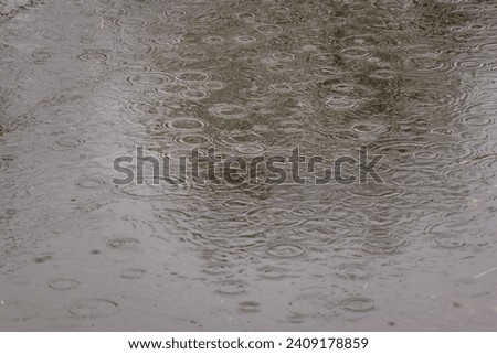 Concept of continuous rain: Raindrops fall onto a large body of water, such as a lake, waterway, flooded area, or a large puddle