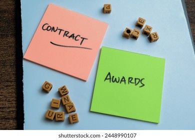 Concept of Contract Awards write on sticky notes isolated on Wooden Table.