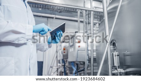 Concept control food industry banner. Factory worker inspecting production line tanker in of dairy with computer tablet.