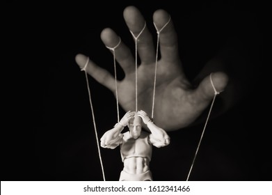 Concept of control. Marionette in human hand. Black and white image