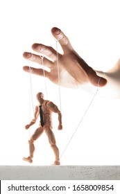Concept of control. Marionette in human hand. Image on white.