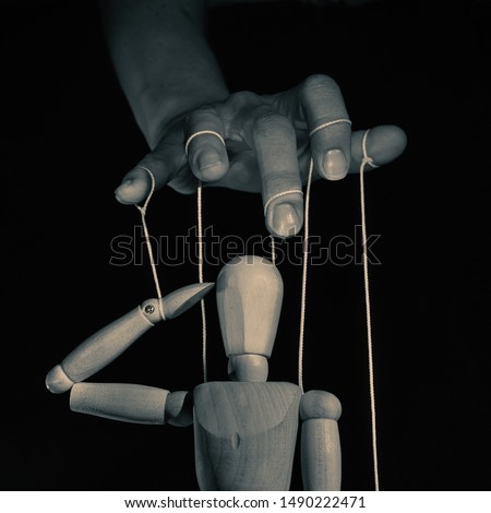 Concept of control. Marionette in human hand l, black and white. Image.