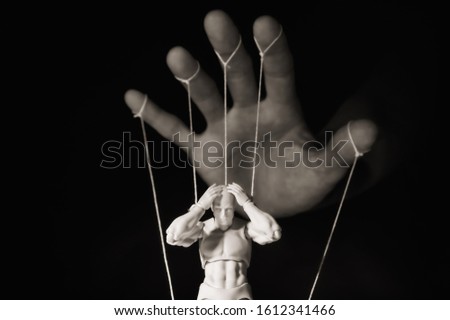 Concept of control. Marionette in human hand. Black and white image