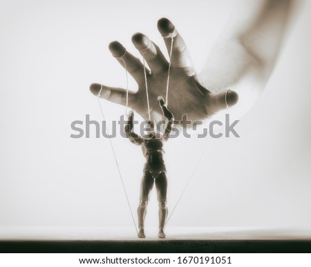 Concept of control. Marionette in human hand. Black and white image.