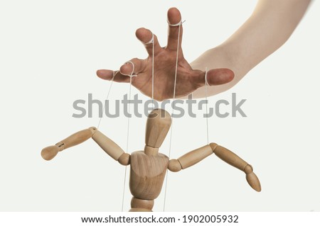 Concept of control. Marionette in human hand. Close-up.