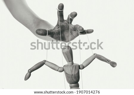 Concept of control. Marionette in human hand. Close-up. Black and white.