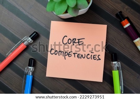 Concept of Core Competencies write on sticky notes isolated on Wooden Table.