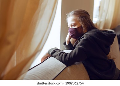 Concept of coronavirus quarantine. Child wearing protective face mask during flu virus, looking out of window. COVID-19 - self isolation. Teen girl forced to stay at home. Prevention epidemic. - Powered by Shutterstock