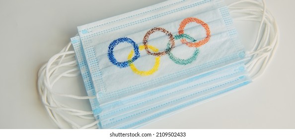 Concept Of Coronavirus Security During 2022 Olympic Games. Olympic Rings Painted On Medical Masks Lying In A Pile On A White Background. Novosibirsk, Russia - 06.01.2022.