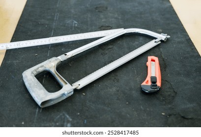 Concept of Craftsmanship and Workspace: Top View of a Workbench with Utility Knife, Saw, Measuring Tape, and Cutting Mat, with Ample Copy Space - Powered by Shutterstock