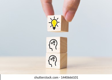 Concept creative idea and innovation. Hand picked wooden cube block with head human symbol and light bulb icon
