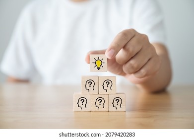 Concept creative idea and innovation. Hand picked wooden cube block with light bulb icon on top pyramid and head human symbol - Shutterstock ID 2079420283