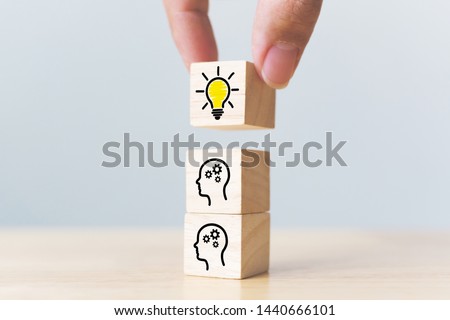Concept creative idea and innovation. Hand picked wooden cube block with head human symbol and light bulb icon