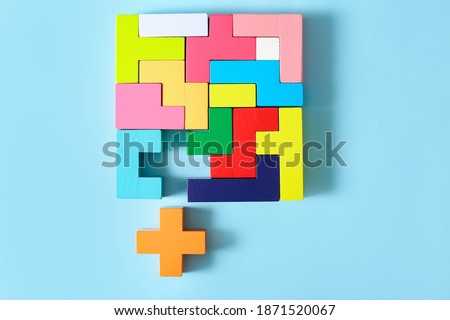Concept of creative, logical thinking. Different colorful shapes wooden blocks on light background. Geometric shapes in different colors. Child development. Riddle and its solution. Logic tasks.
