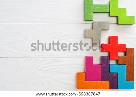  Concept of creative, logical thinking.  Different colorful shapes wooden blocks on white wooden background, flat lay, copy space. Geometric shapes in different colors, top view. Abstract Background.