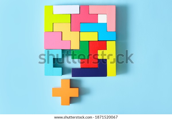 Concept of creative, logical thinking. Different\
colorful shapes wooden blocks on light background. Geometric shapes\
in different colors. Child development. Riddle and its solution.\
Logic tasks.