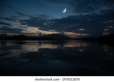 Concept the crescent moon the symbol of Islam begins the eid al Fitr. Seeing the moon in the night sky. The evening sky and the vast river in darkness are beautiful.