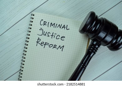 Concept Of Criminal Justice Reform Write On A Book With Gavel Isolated On Wooden Table.