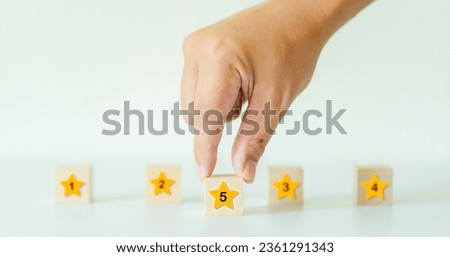 Concept of customer service evaluation and satisfaction survey Customer's hand selects a star with the number five on a wooden cube.