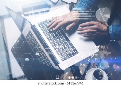 Concept of cyber security.Man working at sunny office on laptop while sitting at the wooden table.Background of digital screen,virtual worldwide connection icon,diagram,graph interfaces.Blurred