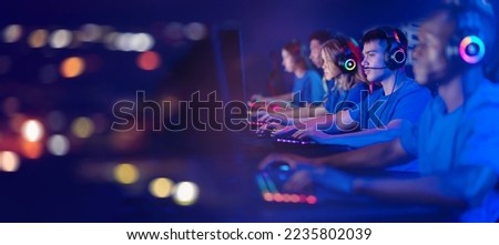 Concept cybersport team banner. Portrait young man gamer with headphones playing in online video game in tournament, neon color light, soft focus.