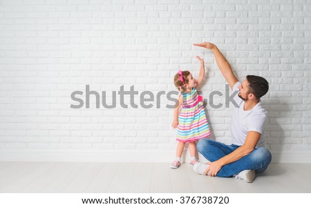 concept. Dad measures the growth of her child daughter at a blank brick wall