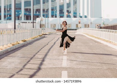 Concept Dancepics Outdoors Dance And Female Beauty. Beautiful Brunette Woman In Black Dress And Pointe Dancing Over City Background. Running Towards The Camera