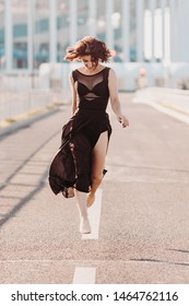 Concept Dancepics Outdoors Dance And Female Beauty. Beautiful Brunette Woman In Black Dress And Pointe Dancing Over City Background. Running Towards The Camera Close Up