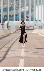 Concept Dancepics Outdoors Dance And Female Beauty. Beautiful Brunette Woman In Black Dress And Pointe Dancing Over City Background. Running Towards The Camera View