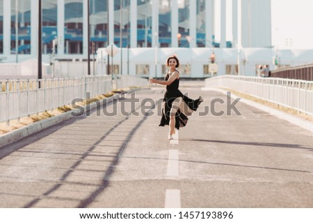 Concept dancepics outdoors dance and female beauty. Beautiful brunette woman in black dress and pointe dancing over city background. running towards the camera