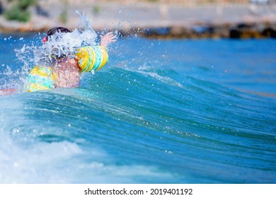 Concept: Dangerous Ocean Waves, Drowning Dangers For Kids And Outdoor Water Safety For Parents. Beautiful Young Girl Swims Alone In The Sea. Horizontal Image.