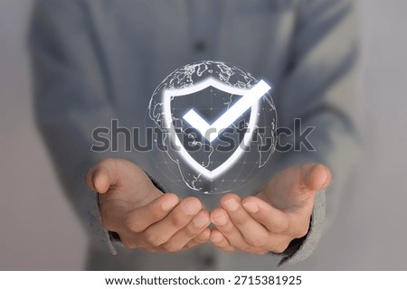 The concept of data protection and security features a businessperson holding a virtual shield with a checkmark icon, representing technology for improving the quality of business services.
