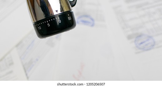The concept of deadline. Mechanical timer at zero against the background of scattered documents.