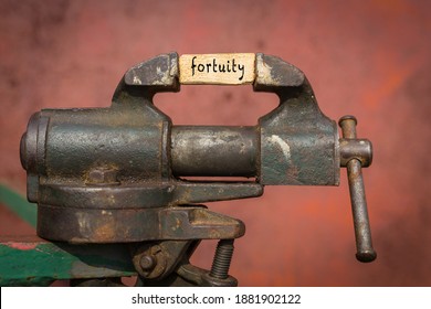 Concept of dealing with problem. Vice grip tool squeezing a plank with the word fortuity