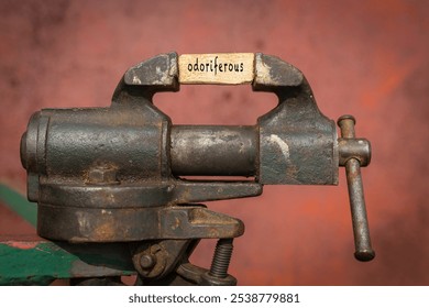 Concept of dealing with problem. Vice grip tool squeezing a plank with the word odoriferous